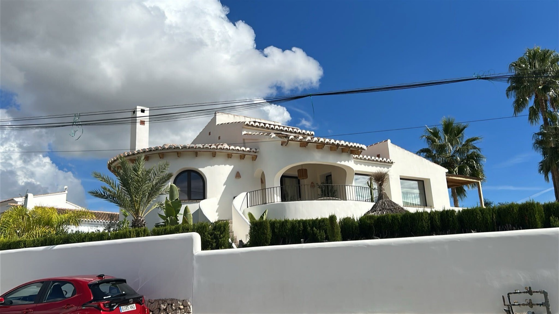 Het huis van Edwin en Jolanda in Jávea: witte villa met bogenterras op de bovenverdieping en een lager niveau eronder.